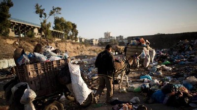 Palestinian workers from the Gaza City municipality use a donkey cart to collect rubbish from the Yarmuk waste dump area